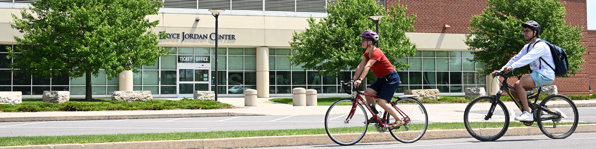 Cyclists riding in front of the Bryce Jordan Center